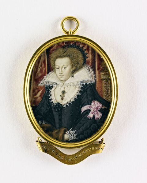 Painting. A miniature head and shoulders portrait of a woman contained within an oval, gold case, with a name inscription attached separately below, and a gold hoop at the top. She wears a black dress and has a large white, pointed collar. A purple ribbon is tied around her left arm. Interior fabrics can just be seen in the distance. 