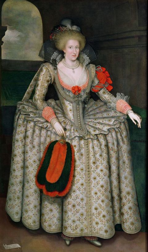Painting. A full-length portrait of a woman dressed in formal, historical clothing within an interior space, with an open, arched window behind her. She wears a silver dress adorned with gold embroidery, holds a red feather fan, and has a red sash tied around her left arm. 