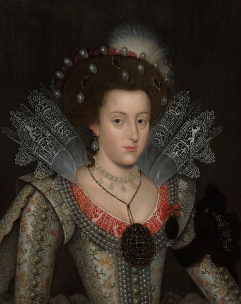 Painting. A portrait of a young woman seen from head to shoulders, dressed in elaborate, historical costume. She wears a silver, corseted dress featuring an intricate floral pattern and red detailing along the front. A stiff lace collar protrudes from the neckline and her hair is decorated with jewels and a feather.
